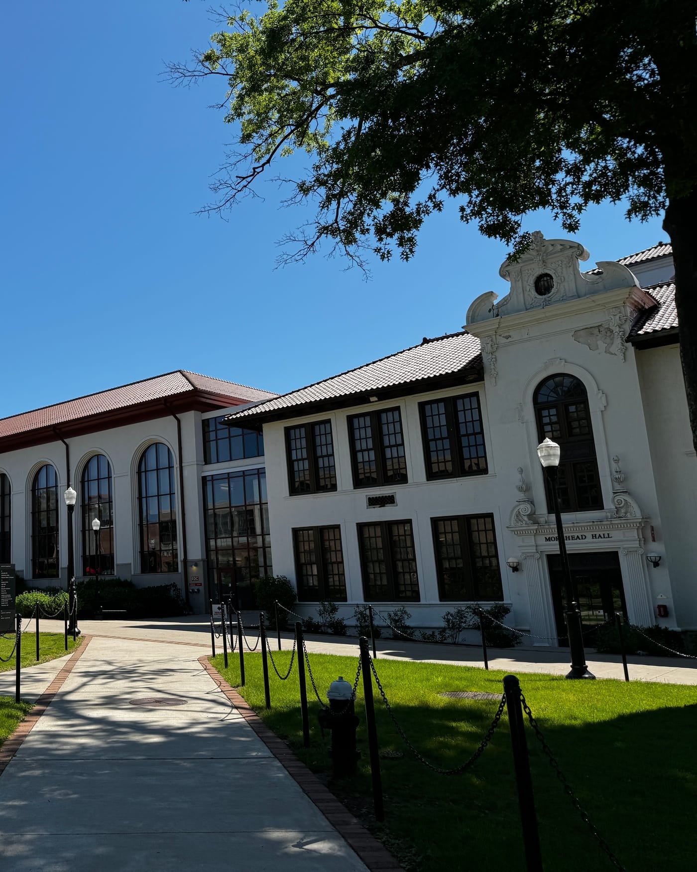 White Spanish-style university building with a red tile roof under a blue sky