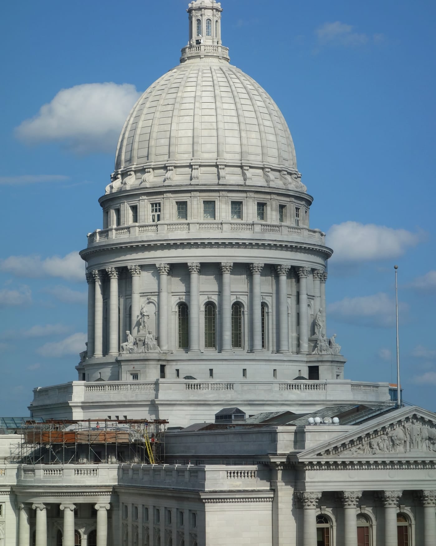 White stone dome and columns of a state capitol against a blue sky