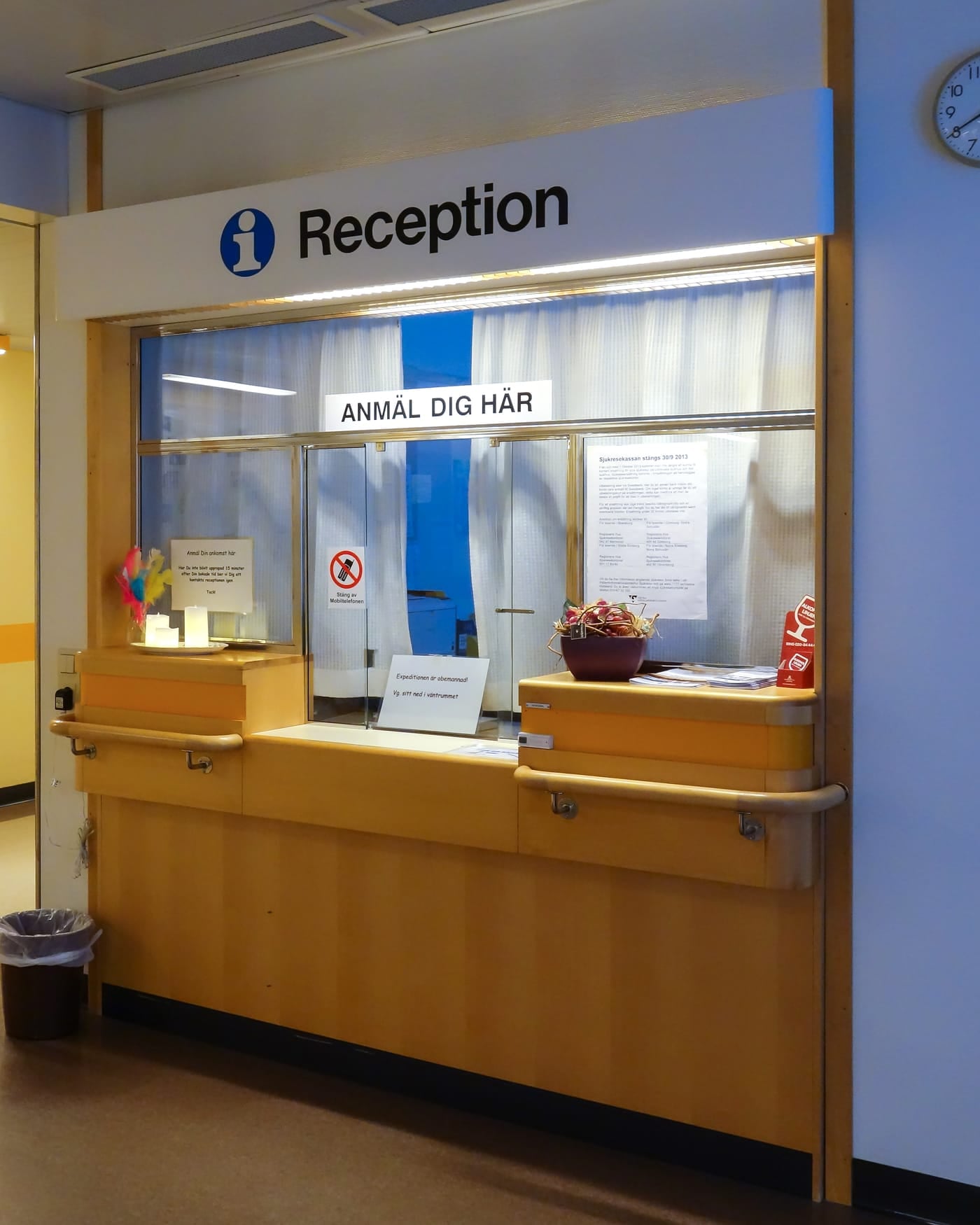 Hospital reception counter with a glass window in a corridor with orange and blue walls