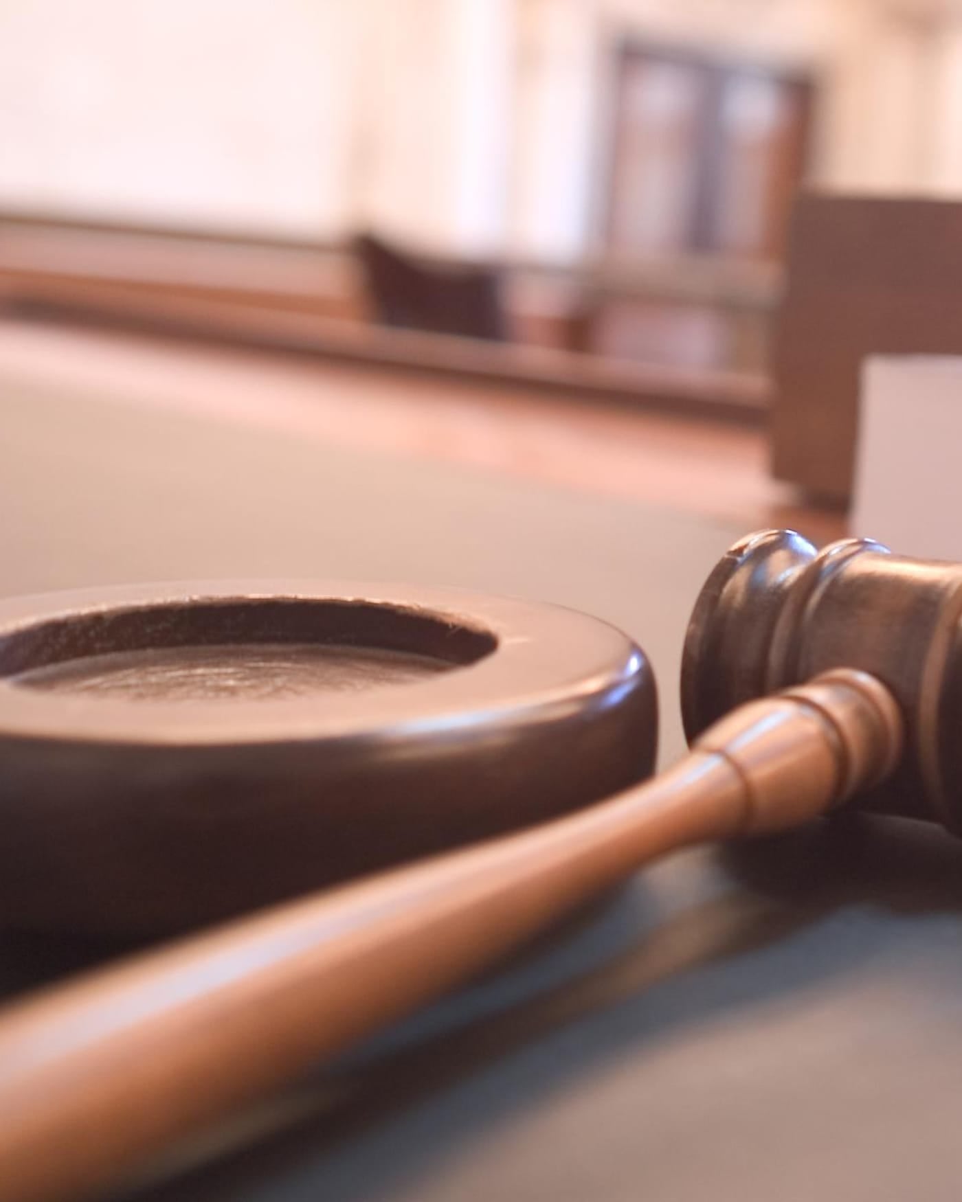 Wooden gavel resting on a courtroom desk, shallow focus