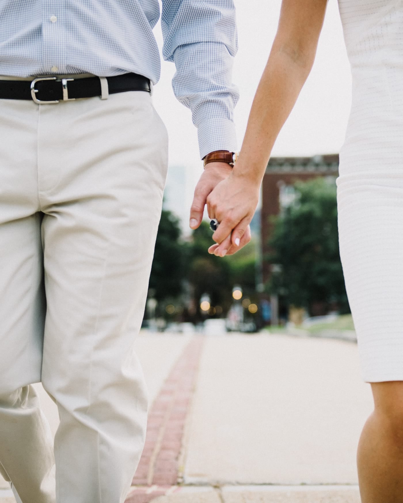 Two adults holding hands while walking, cropped at the waist