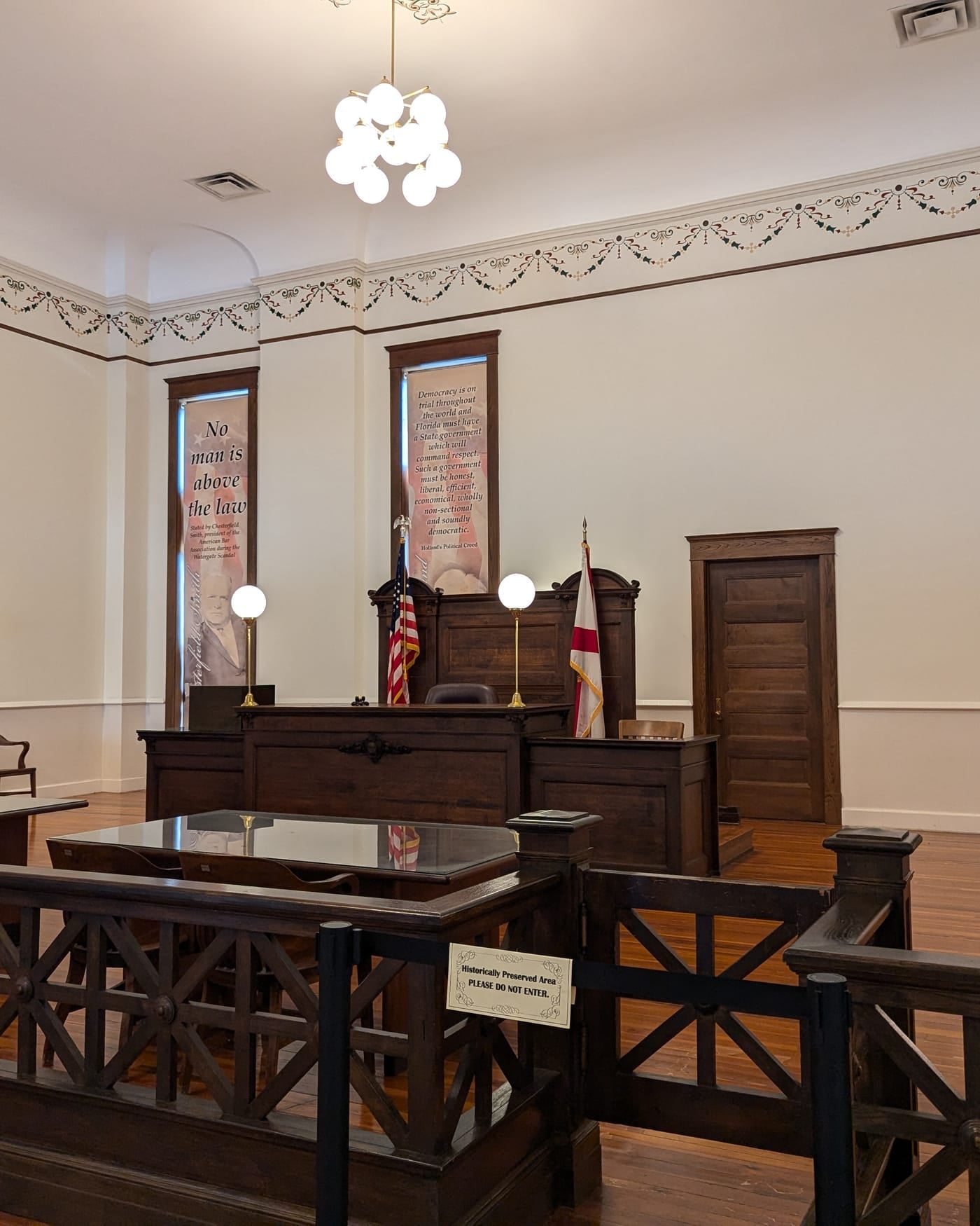 Restored 1908 courtroom with wooden railings, a judge's bench and a chandelier