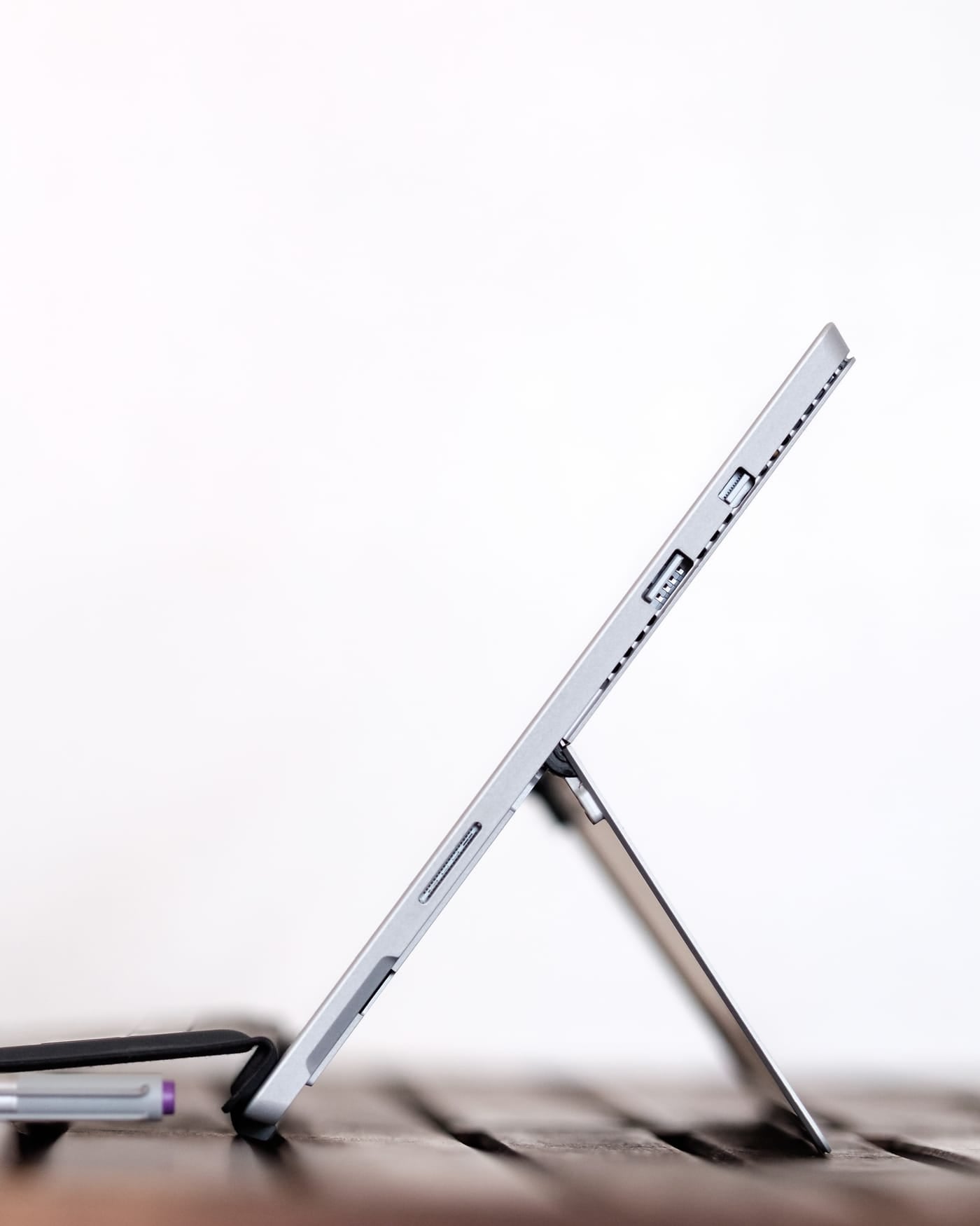 Slim tablet propped upright on its kickstand on a white desk