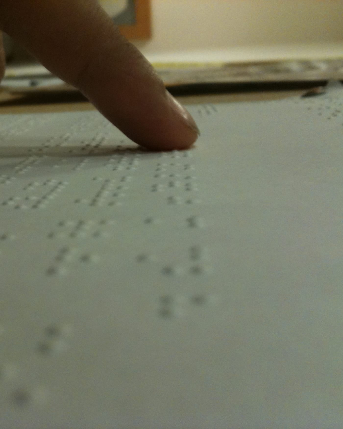 Close-up of a fingertip reading raised braille dots on a page