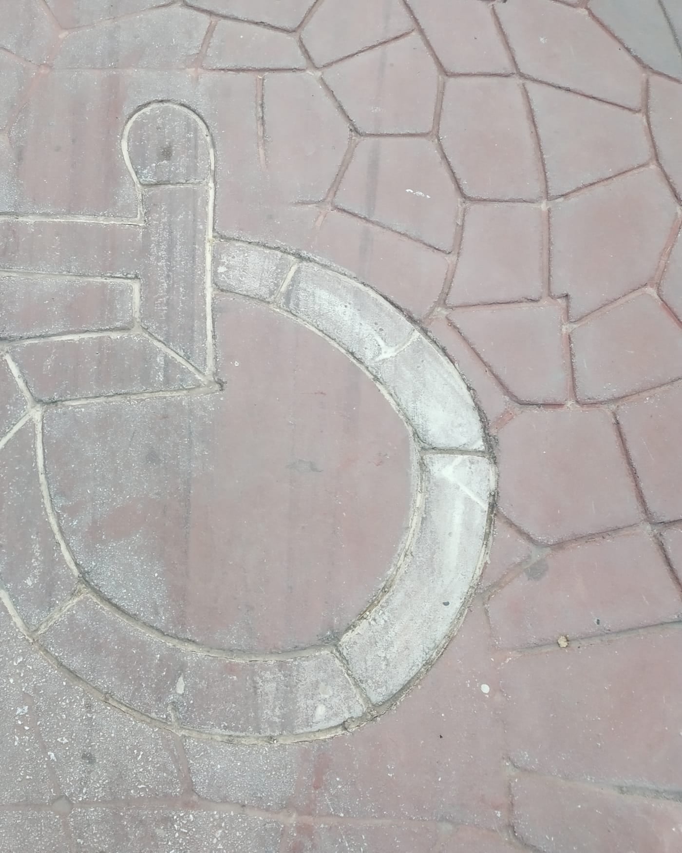 Wheelchair accessibility symbol laid into red paving stones