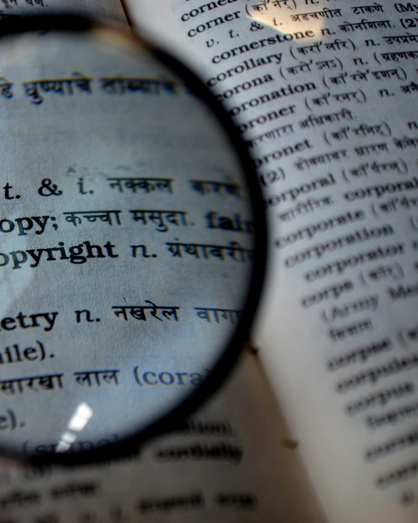 Magnifying glass held over a printed bilingual dictionary page