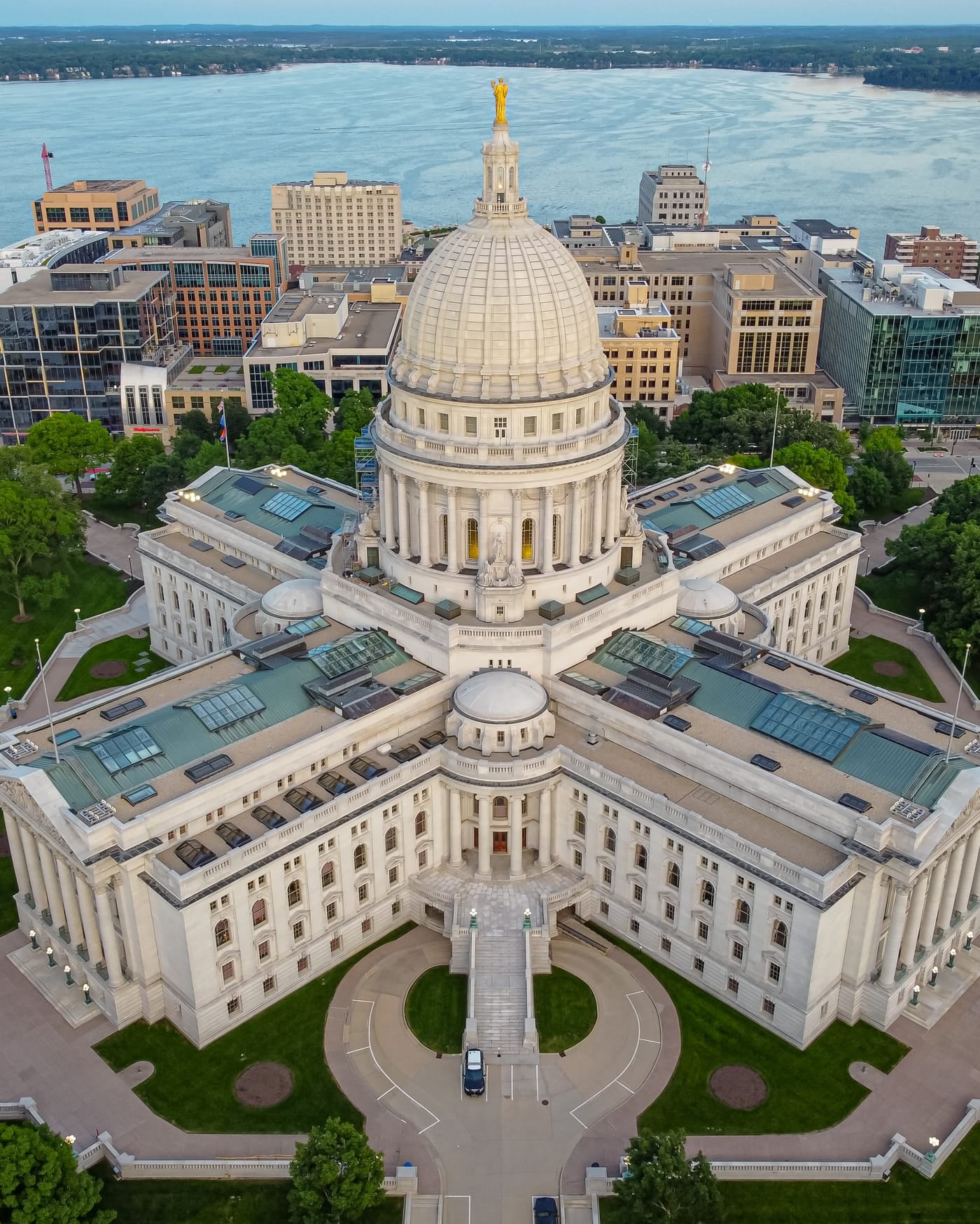 Aerial view of a domed state capitol building surrounded by city blocks and a lake