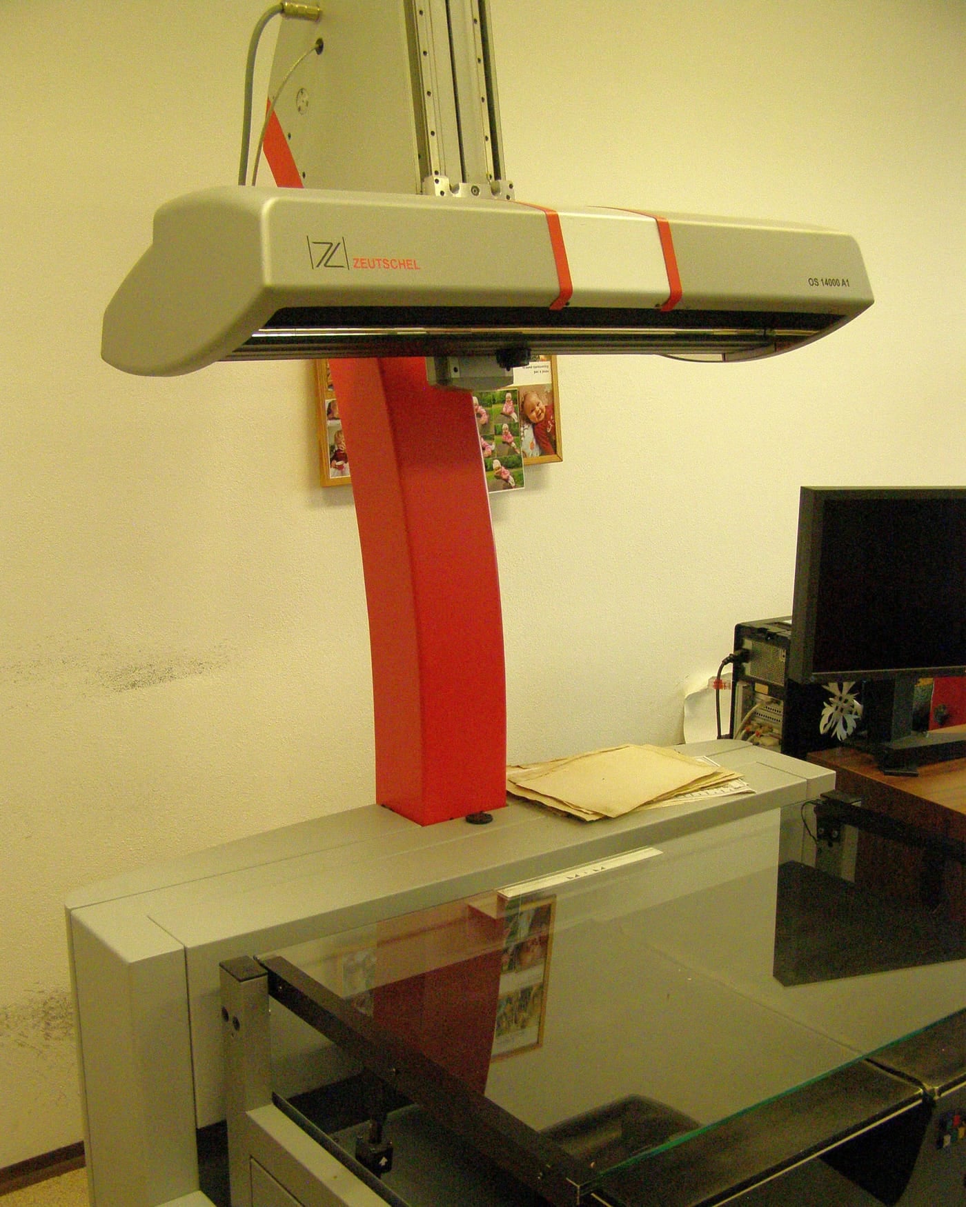 Overhead book scanner with a red arm in an archive reading room