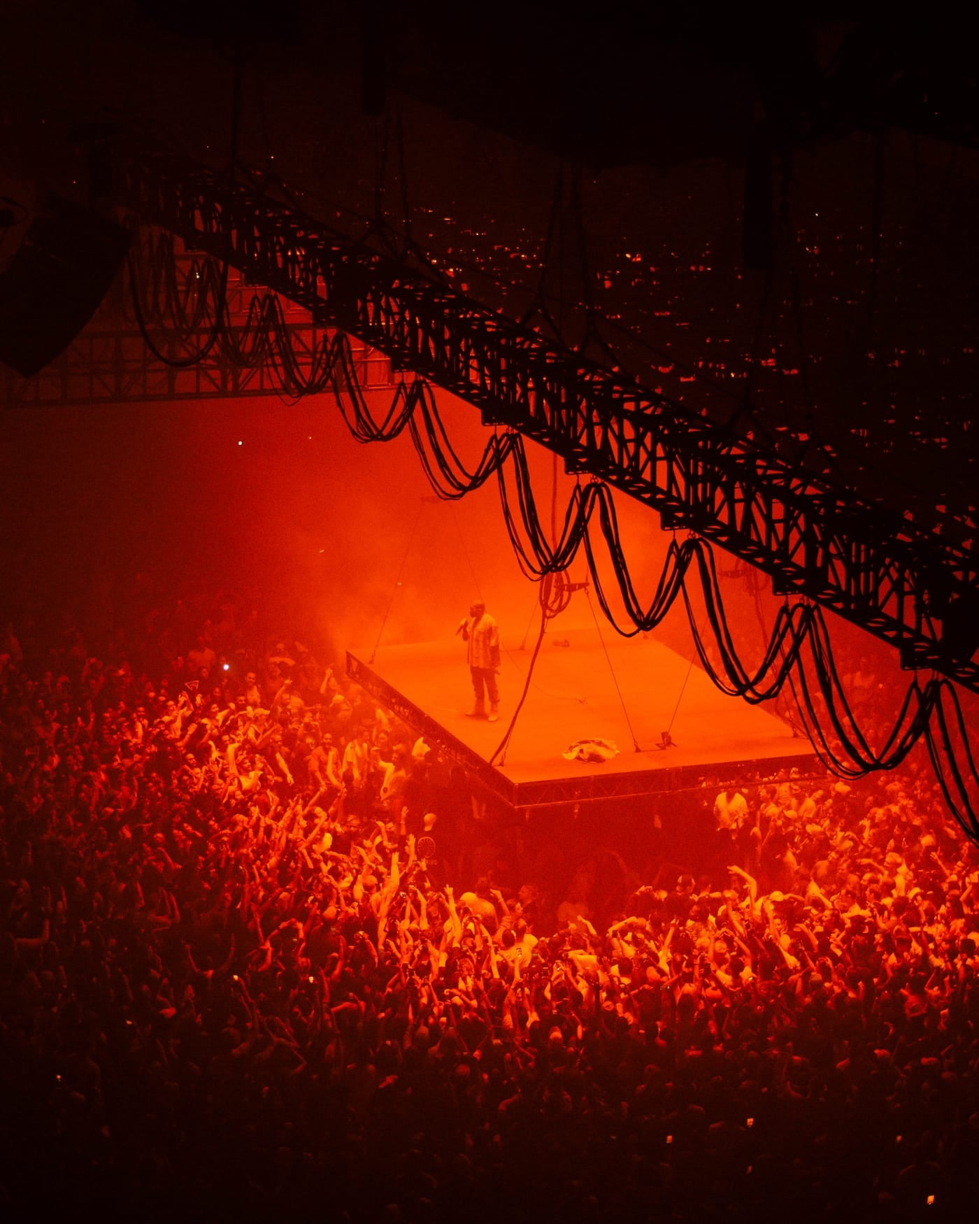 Arena crowd around a suspended stage lit entirely in red light