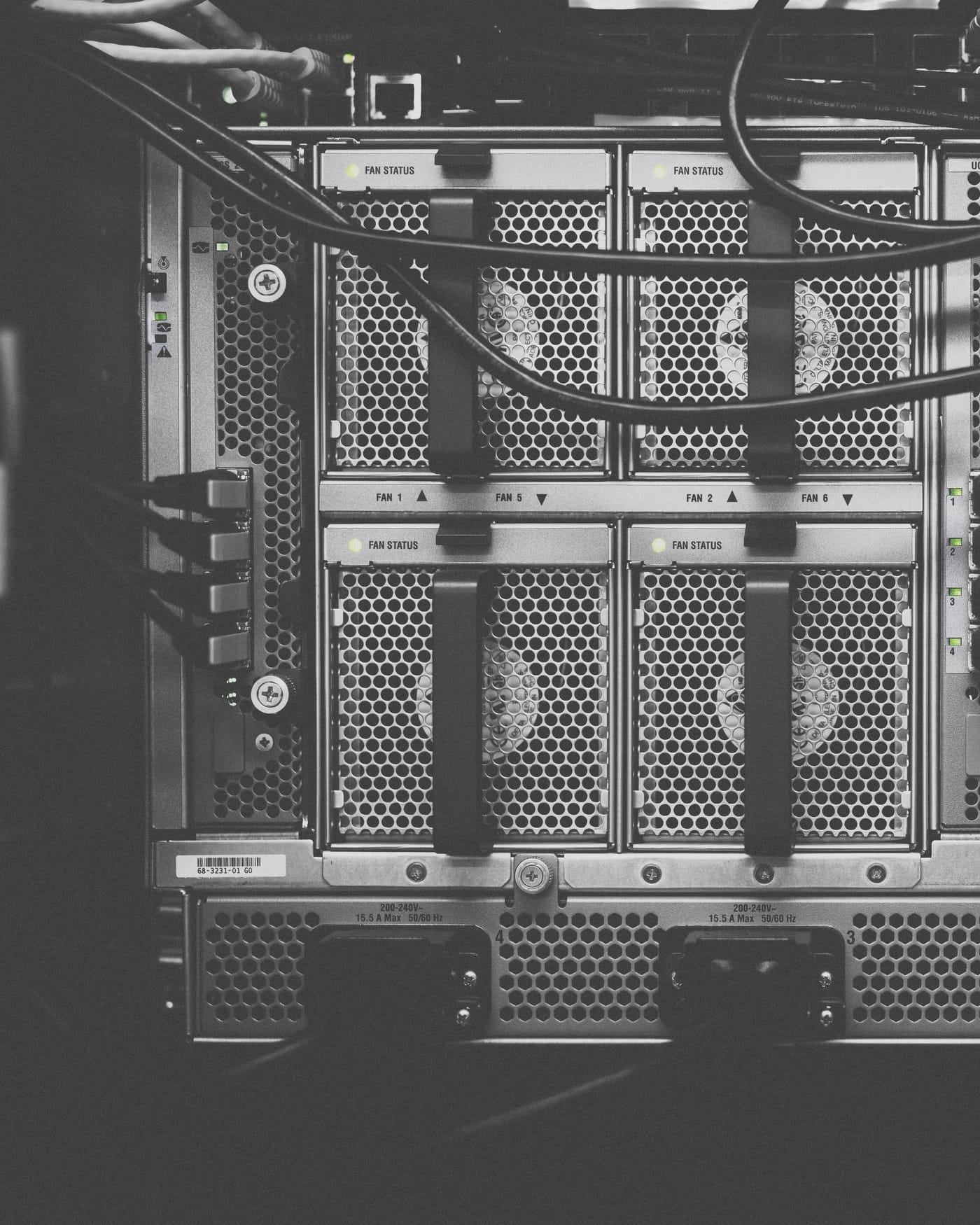 Black-and-white close-up of a server rack with fan grilles and cables