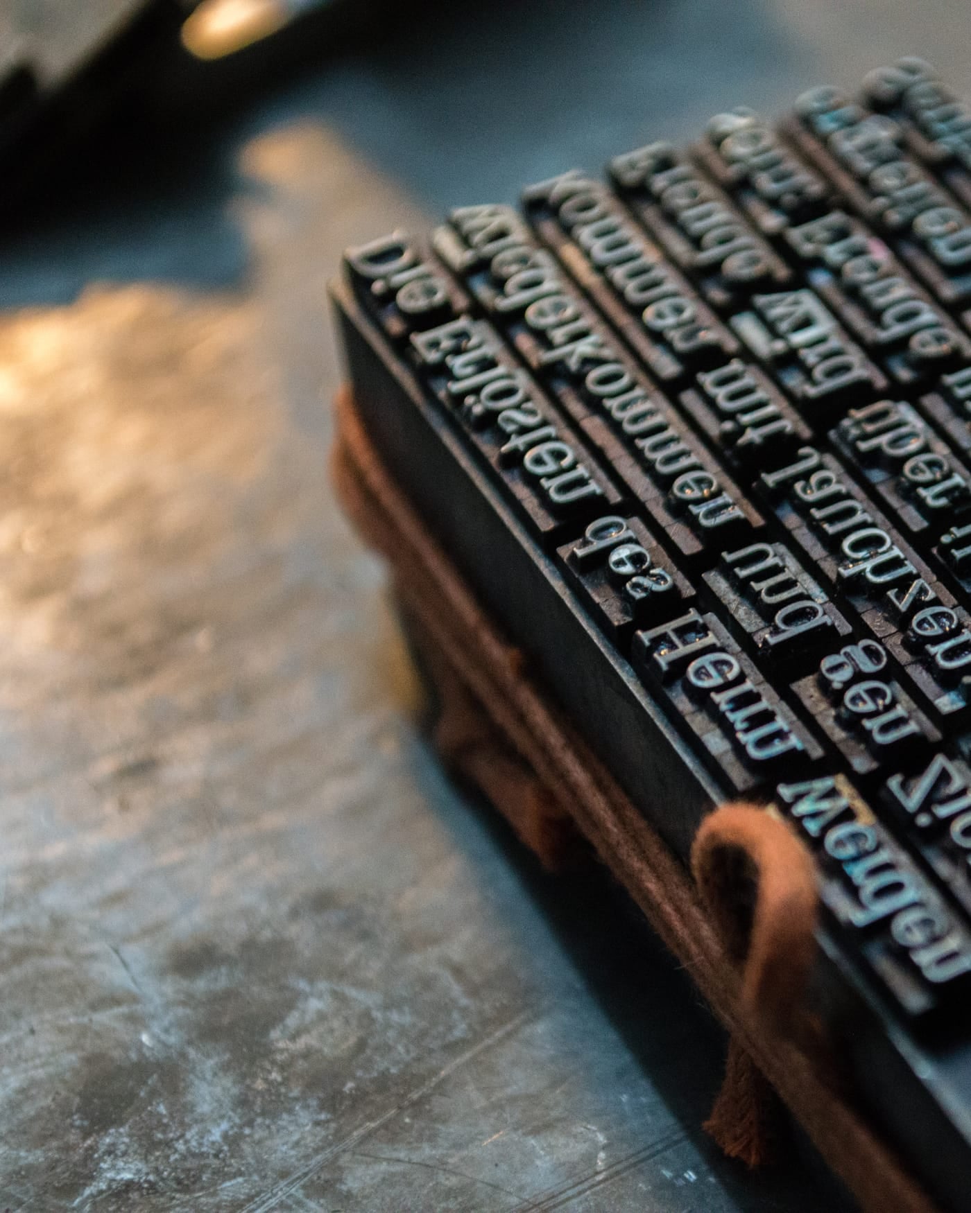 Block of metal letterpress type tied with string on a dark workbench