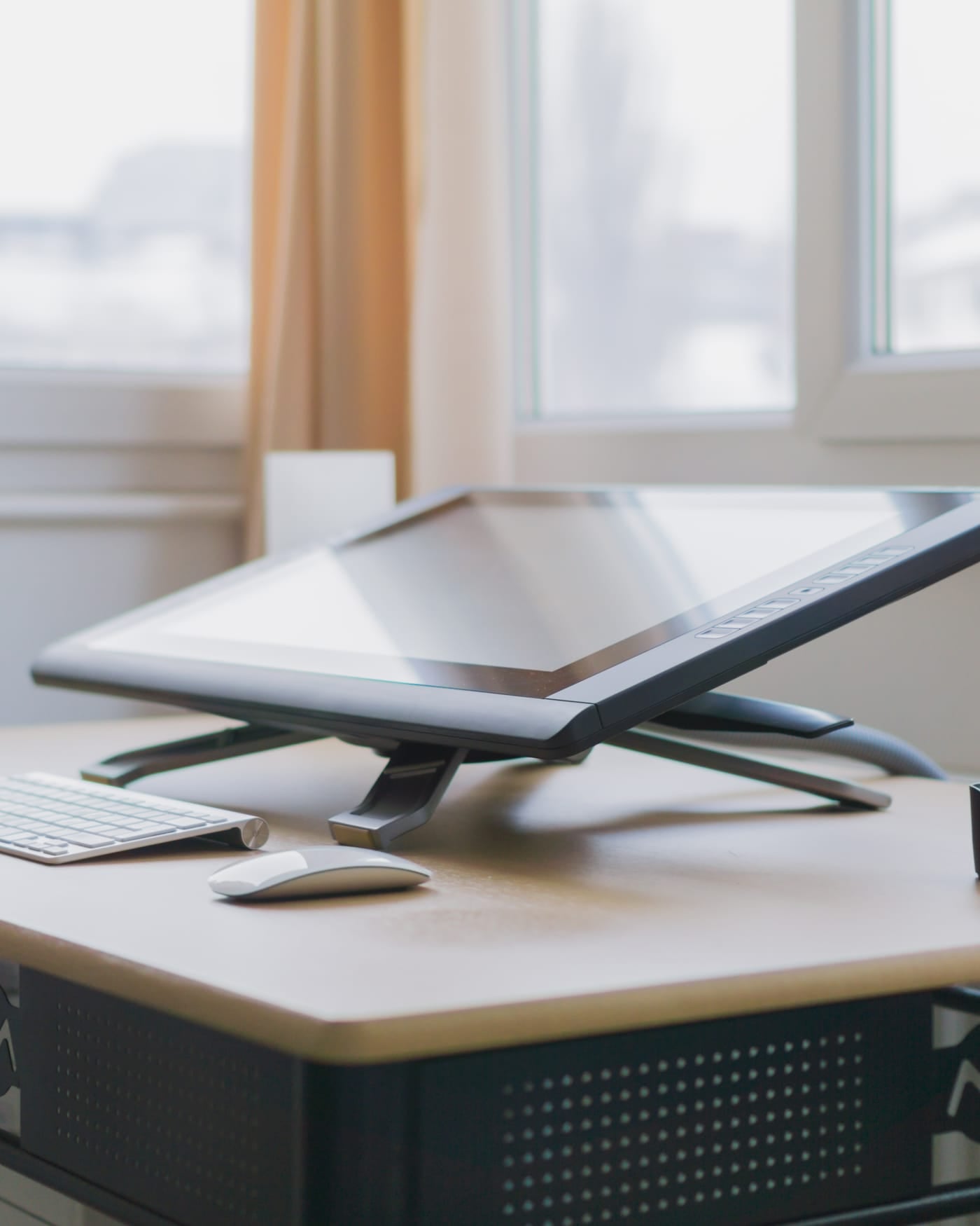 Pen display tablet on a stand at a bright designer's desk by a window