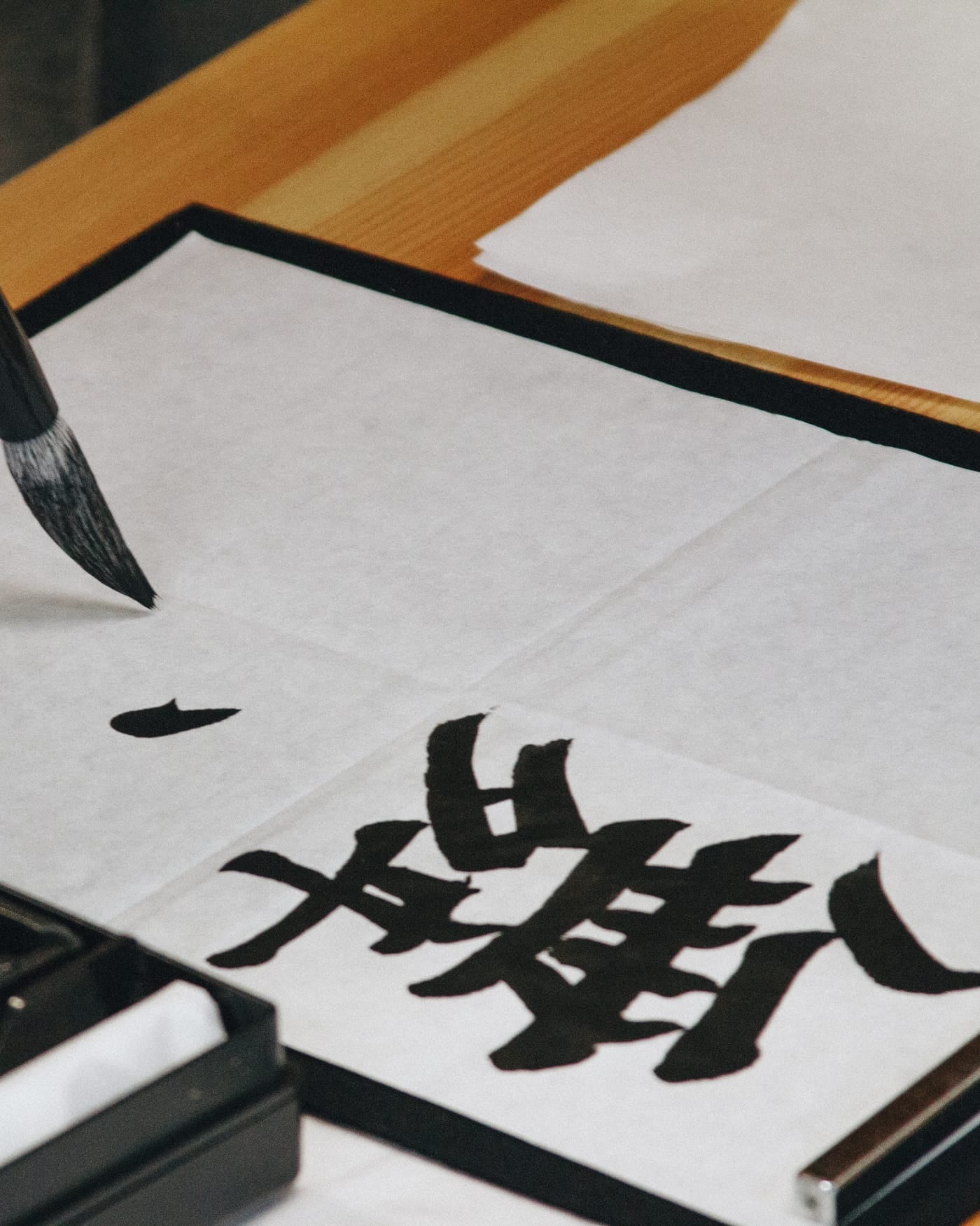 Hand painting Japanese kanji characters on white paper with a calligraphy brush