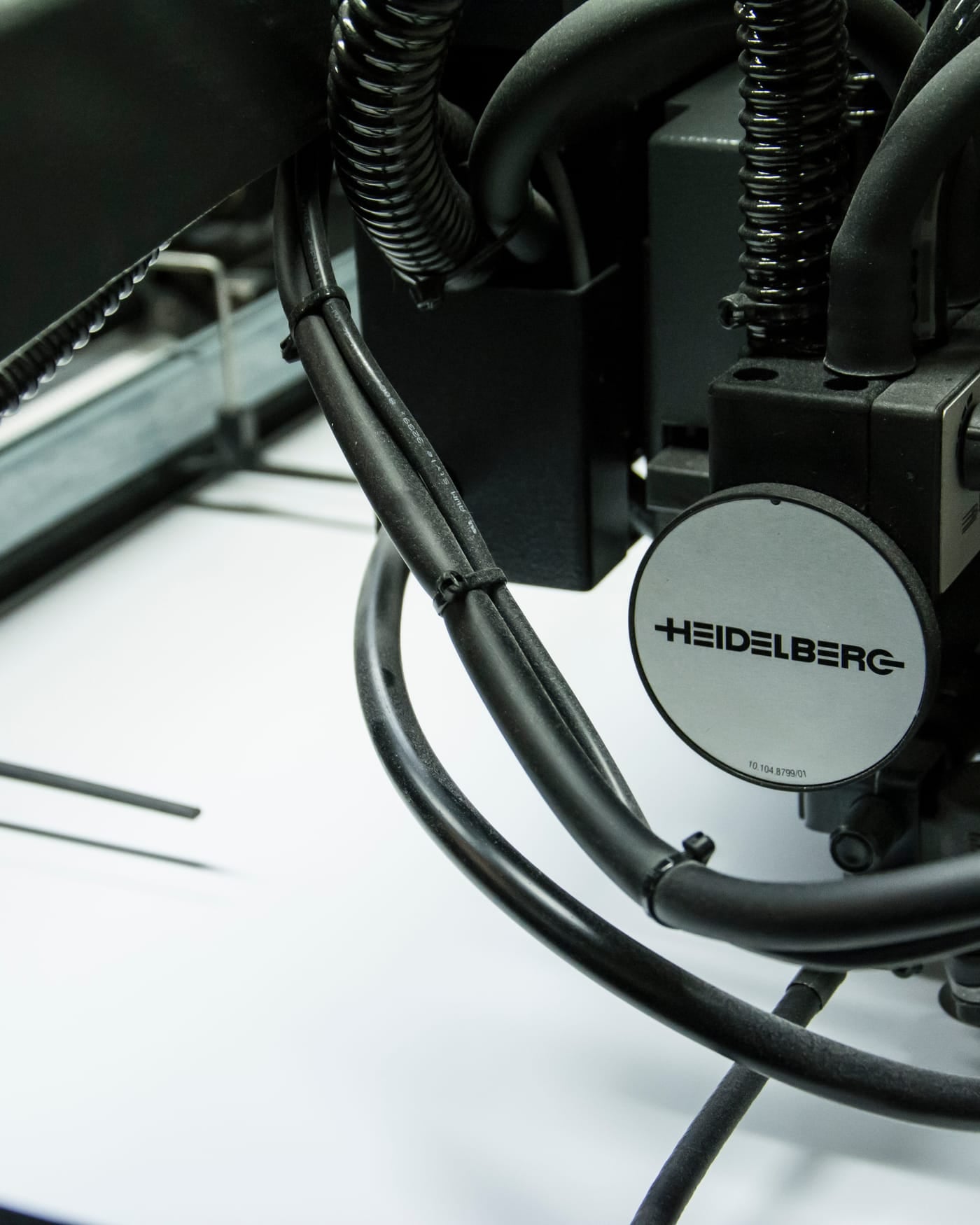 Close-up of a Heidelberg offset printing press feeding a white sheet of paper
