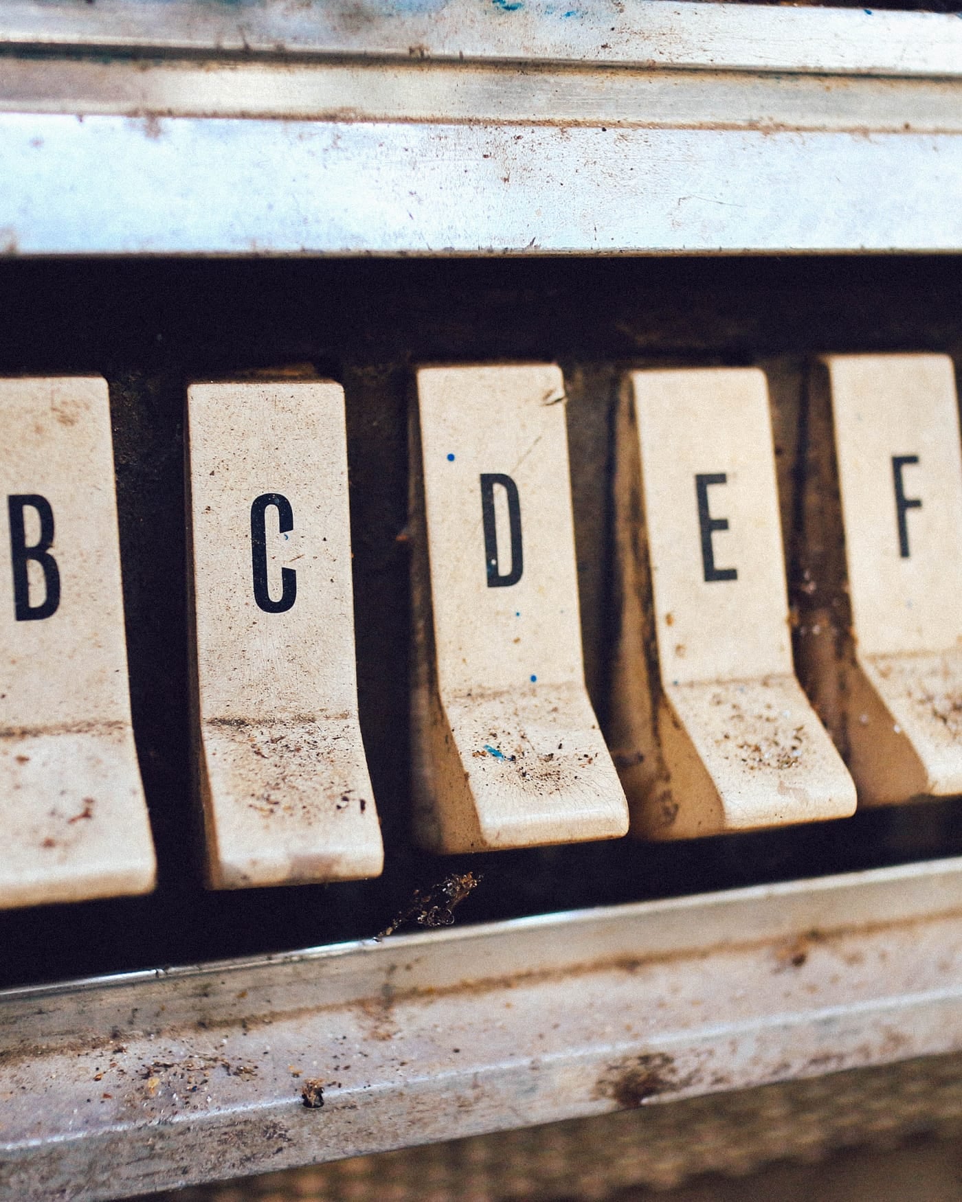 Row of worn vintage letter keys on an old typesetting machine