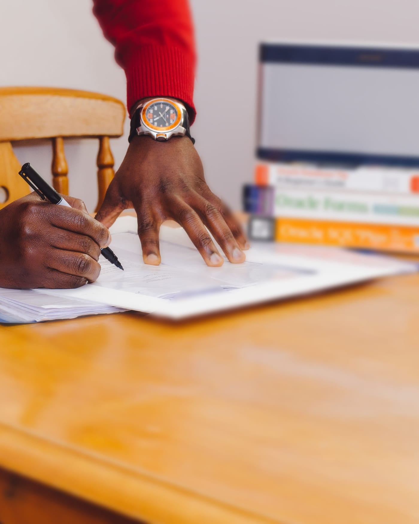 Hand writing notes with a pen on paper at a wooden desk