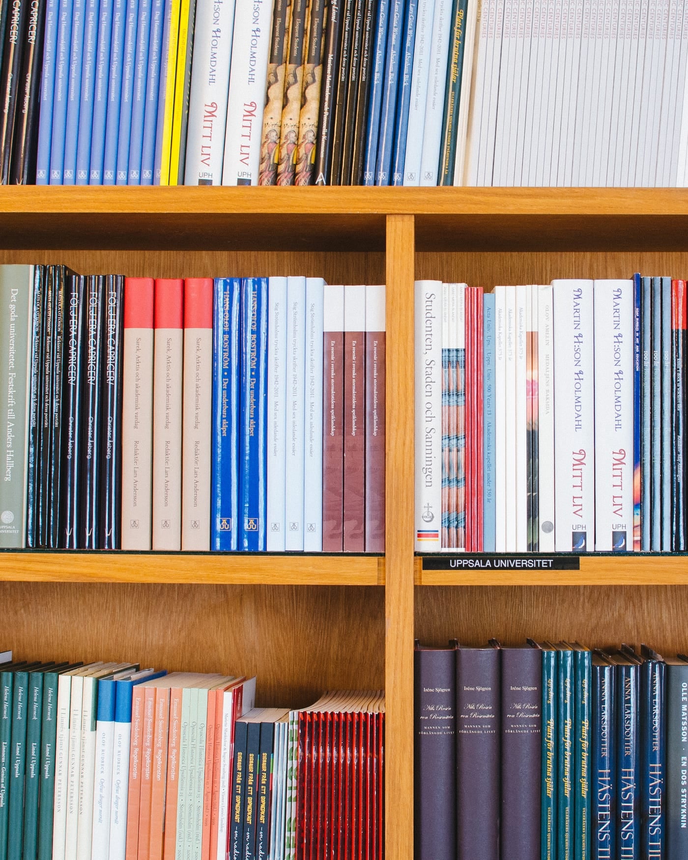 Wooden library shelves lined with rows of bound academic volumes