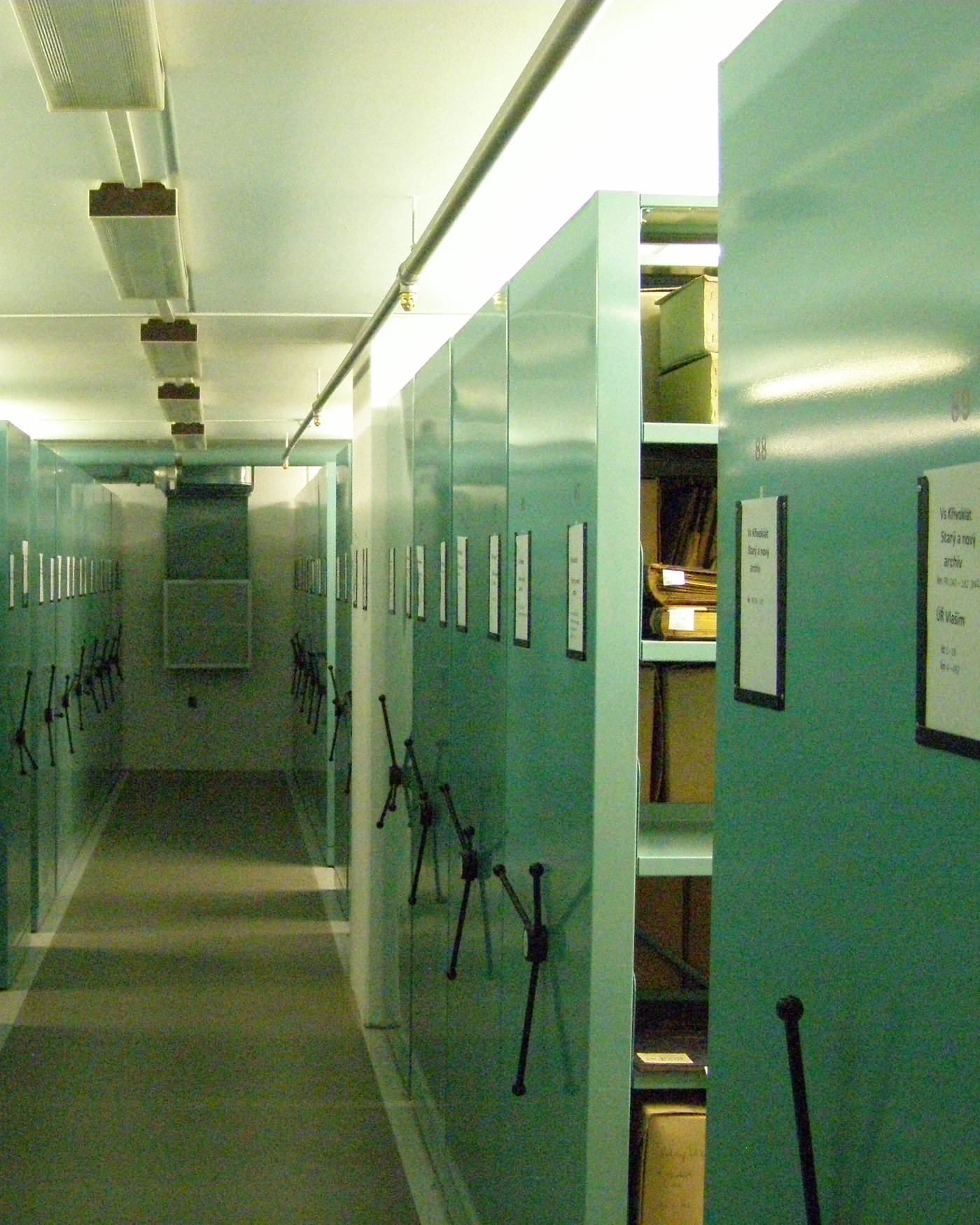 Corridor of green mobile shelving units in a records archive