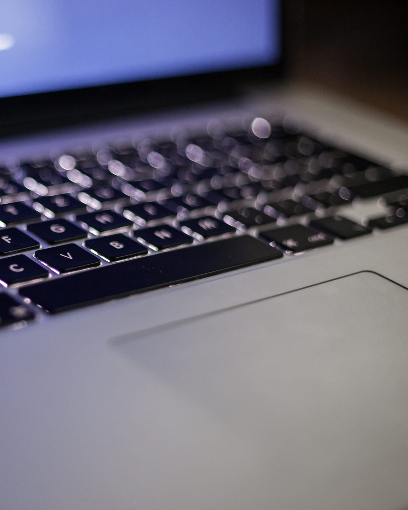 Backlit laptop keyboard glowing in a dark room