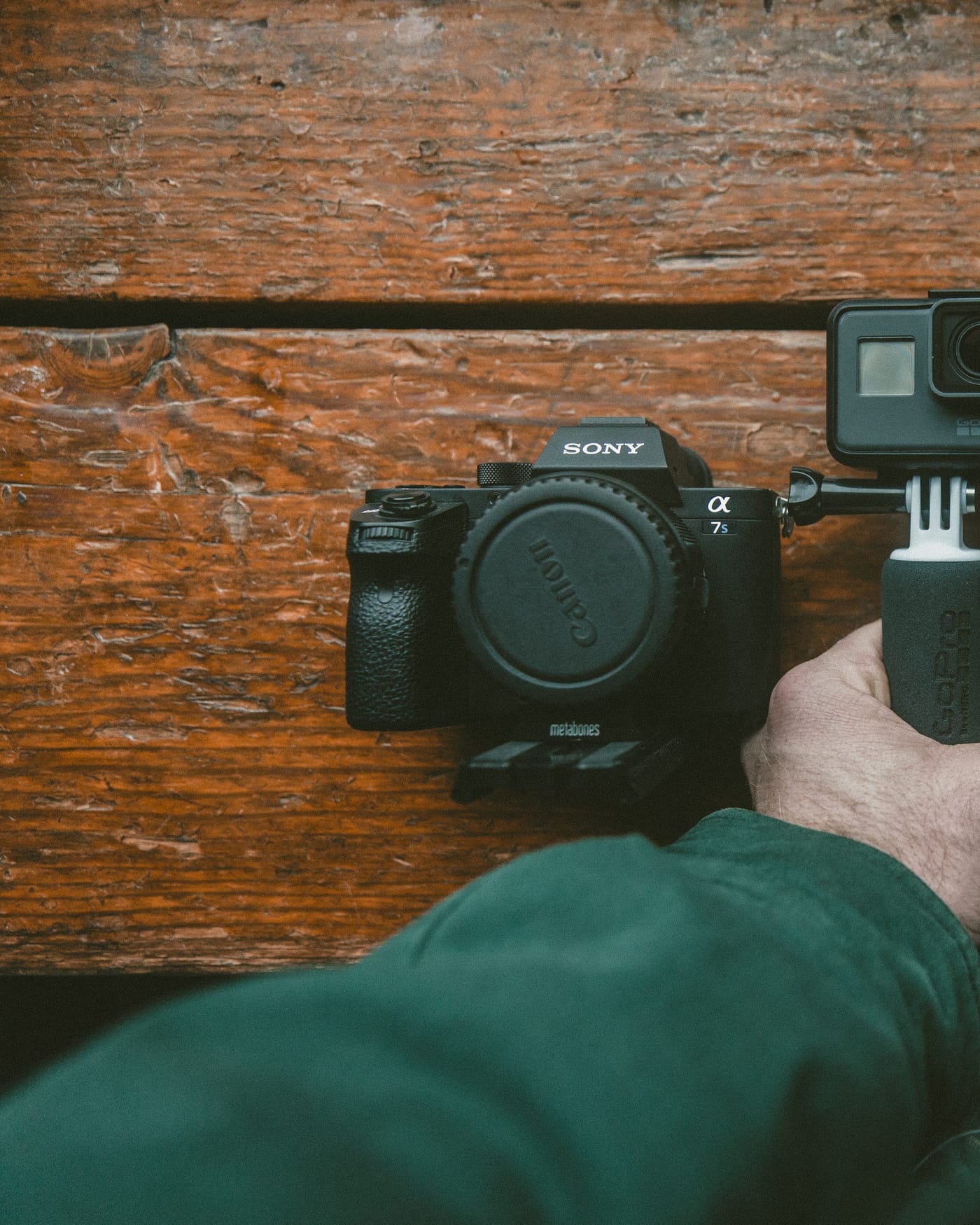 Hands holding a mirrorless video camera over a wooden table