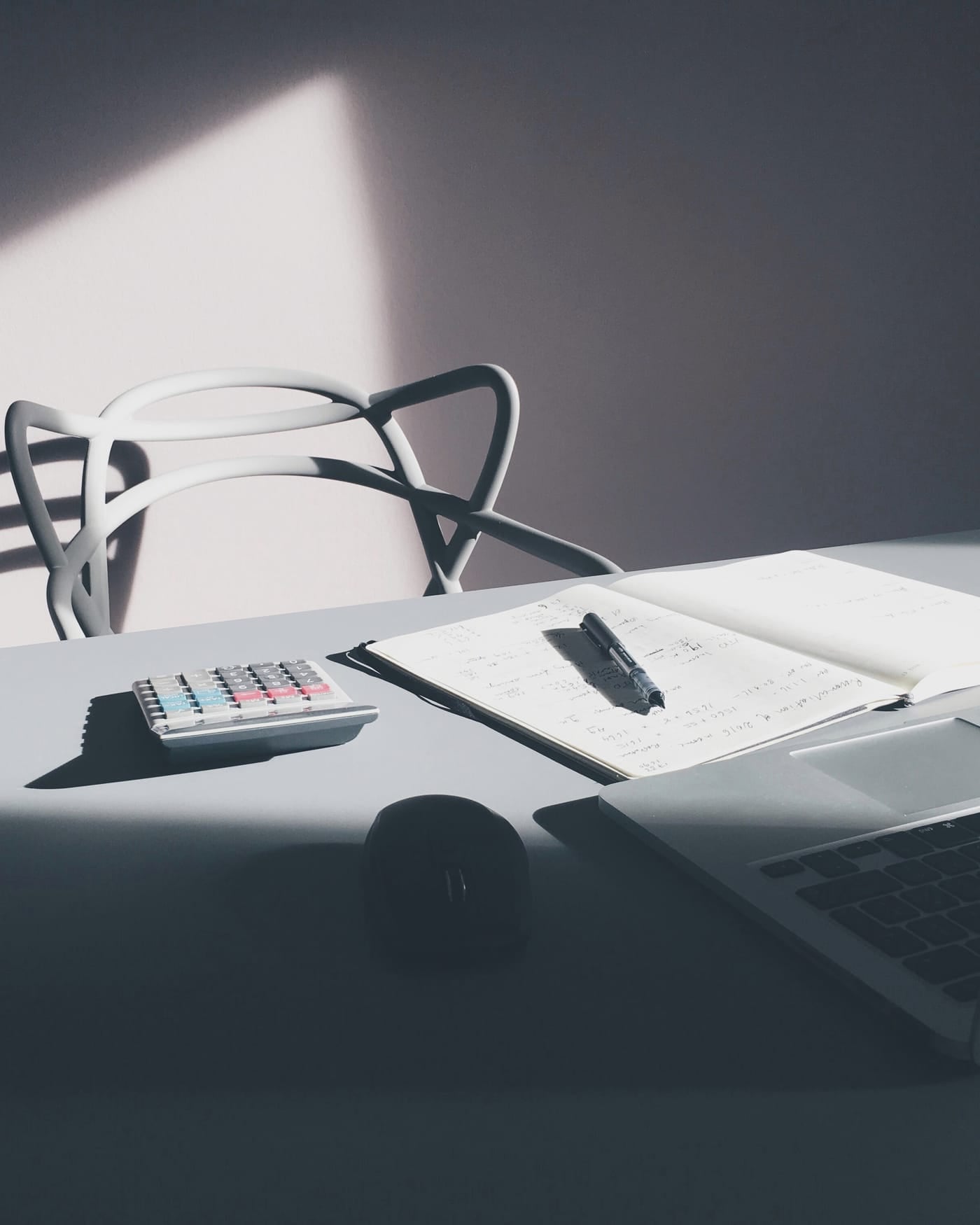 Calculator, notepad and laptop on a desk in low light
