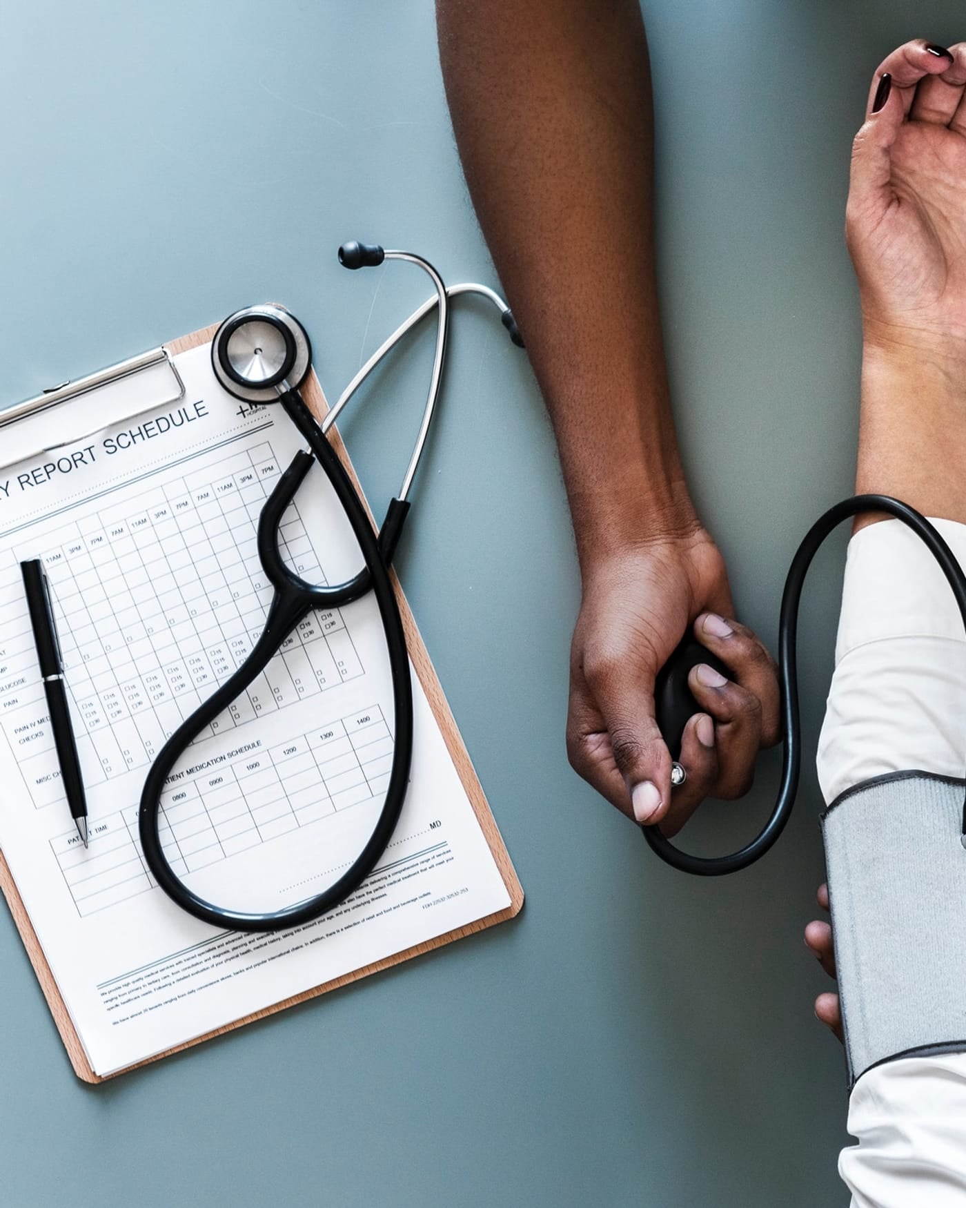 Stethoscope on a clipboard beside a patient having blood pressure taken