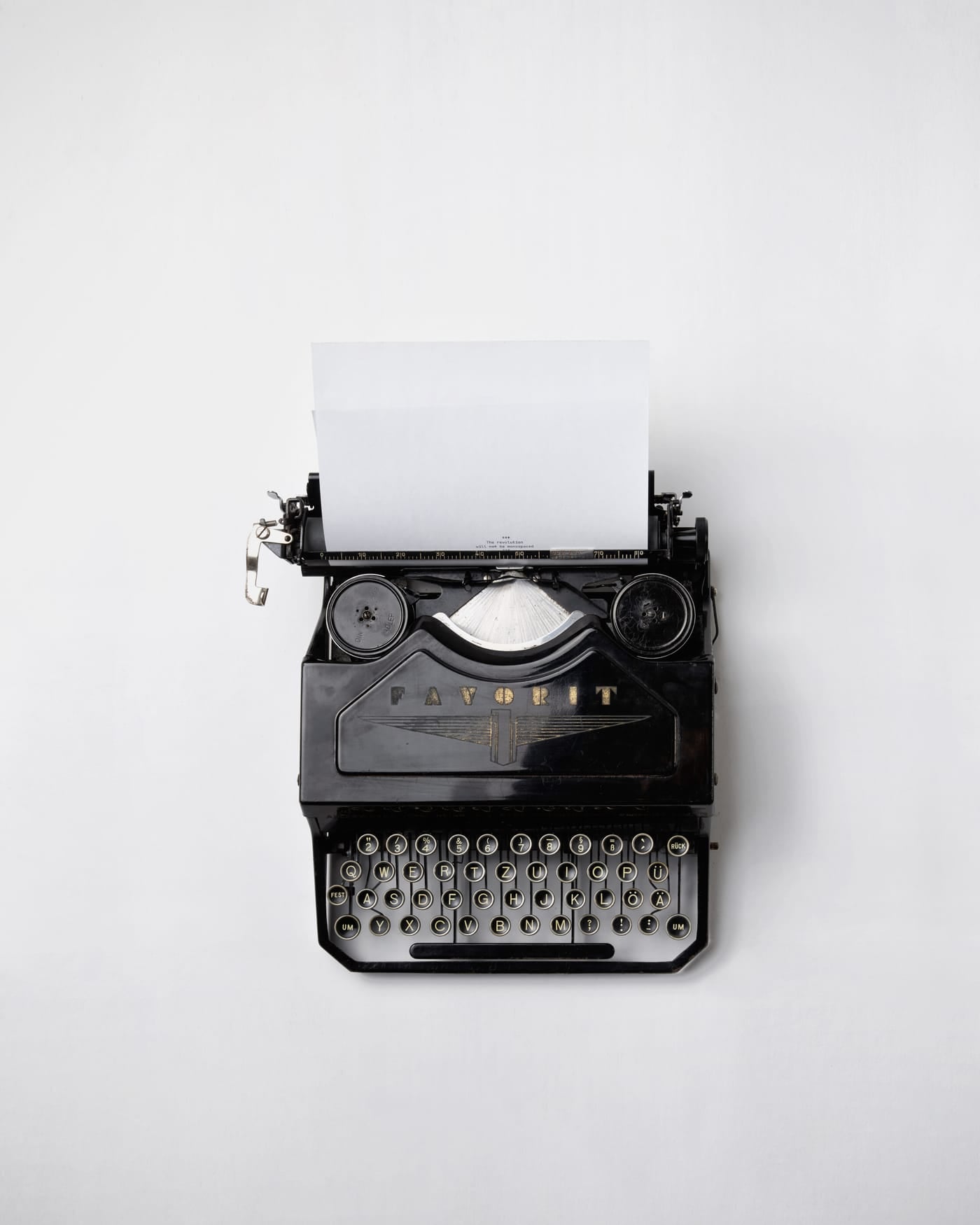 Vintage black typewriter with a blank sheet of paper on a white desk