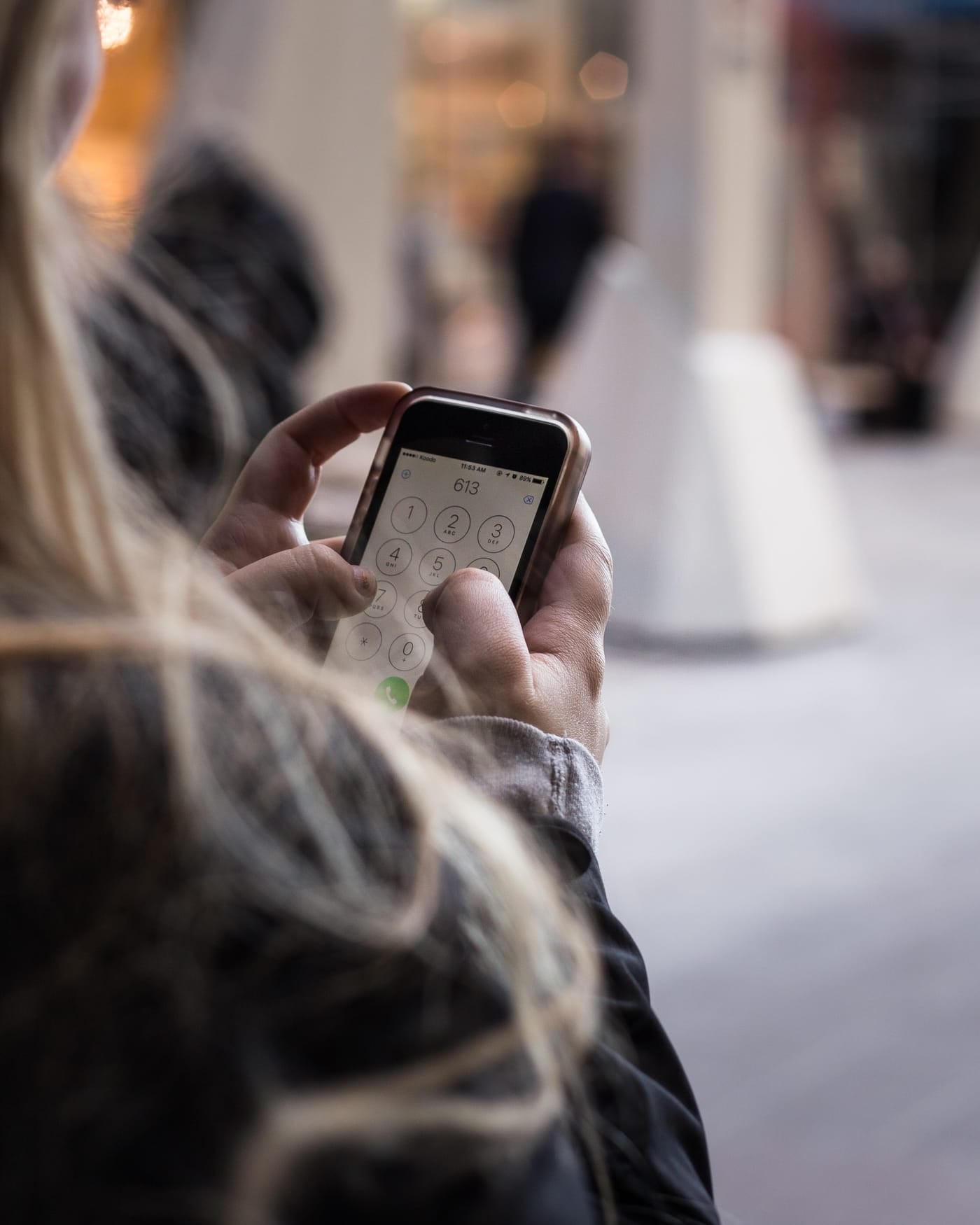 Woman seen from behind using a smartphone inside a bright shopping hall