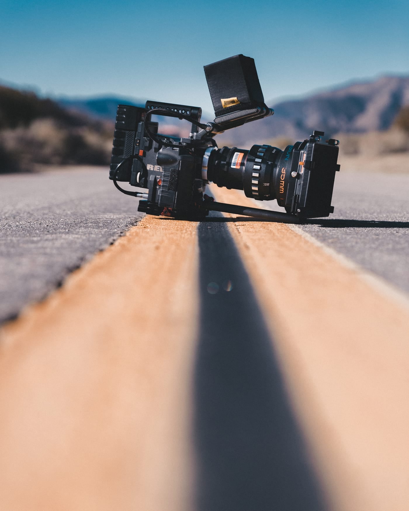 Cinema camera rig standing on an empty desert road with mountains behind