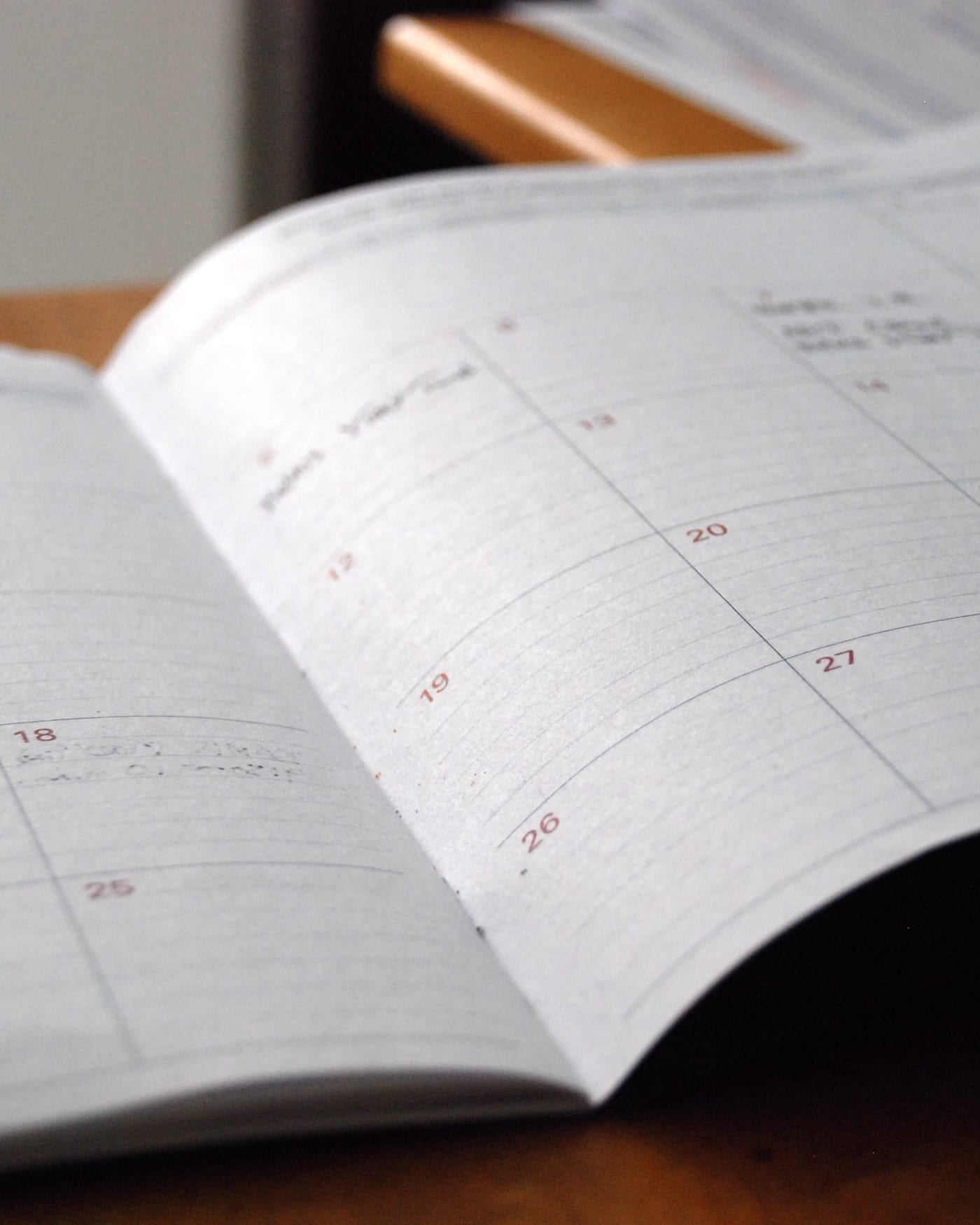 Open monthly planner notebook lying on a wooden desk
