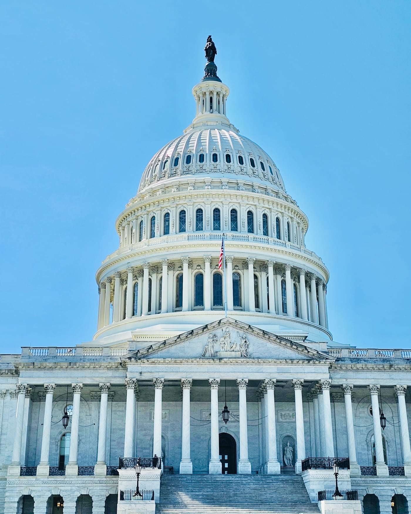 The dome and columned east facade of the United States Capitol under a clear blue sky