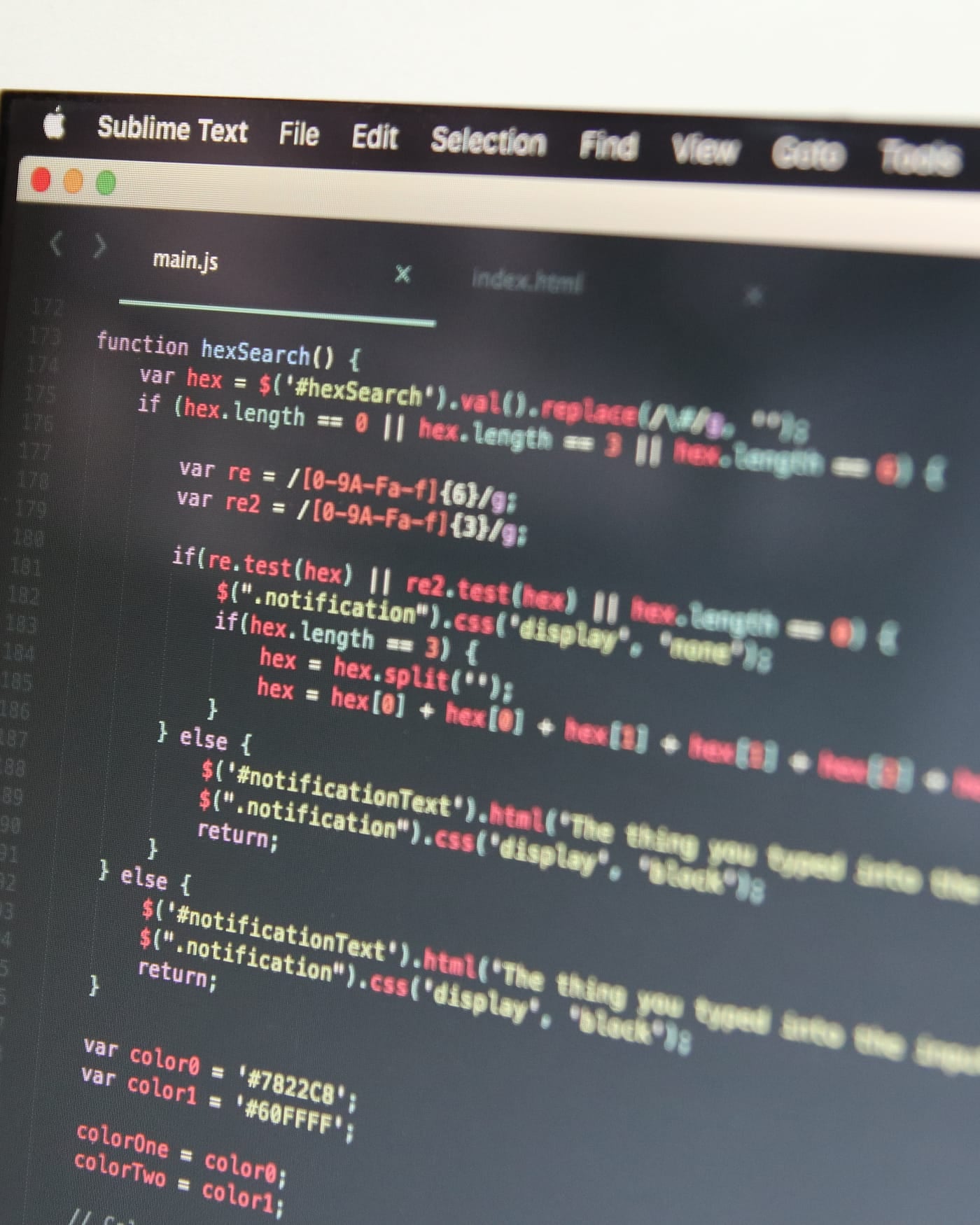 Close-up of a laptop screen showing colorful JavaScript source code in a dark editor