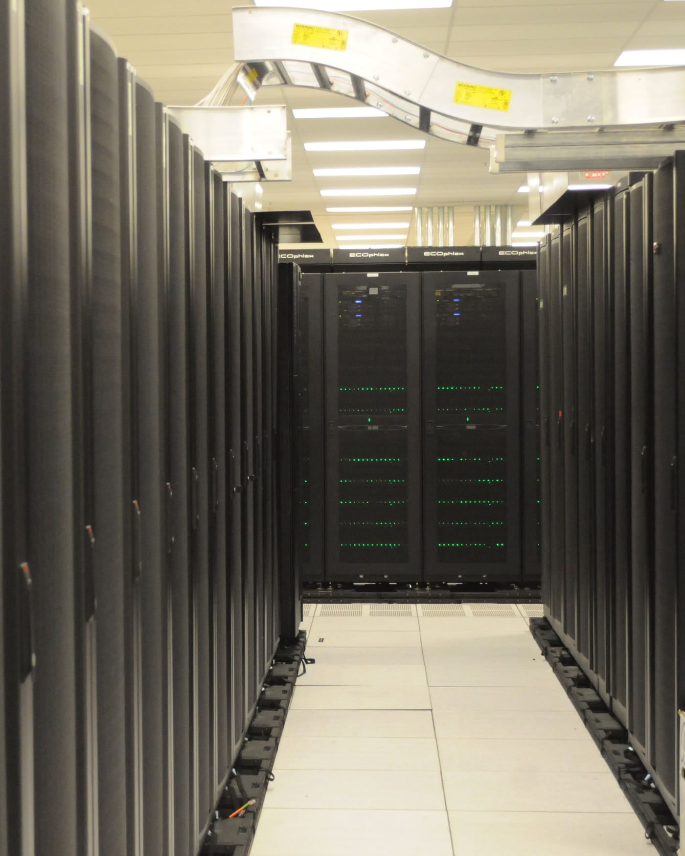 Aisle between rows of black server racks in a data center