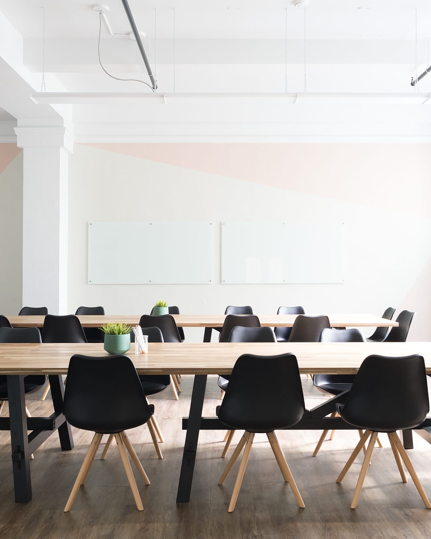 Long wooden conference table with black chairs in a large white meeting room