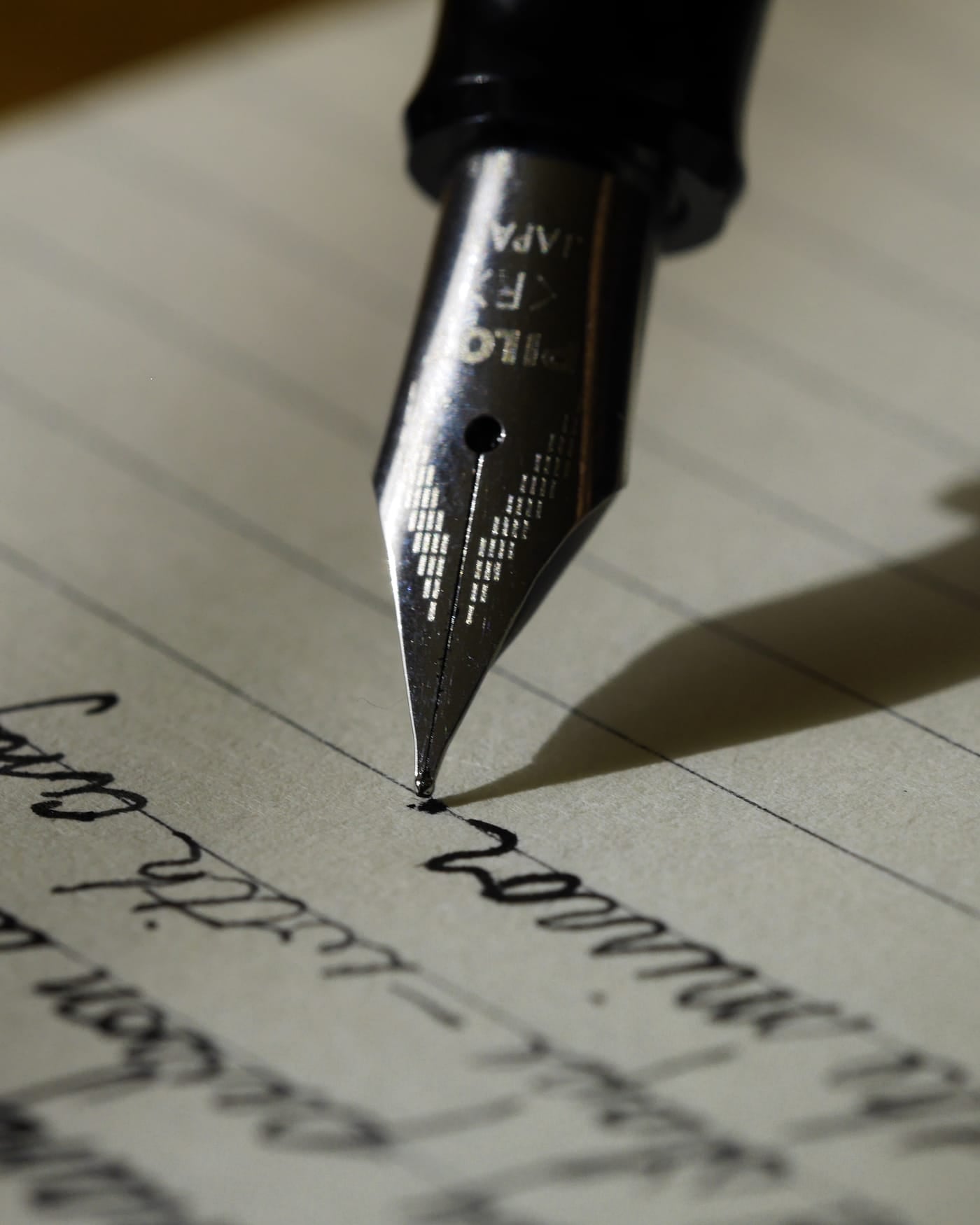 Fountain pen nib writing in cursive on lined paper