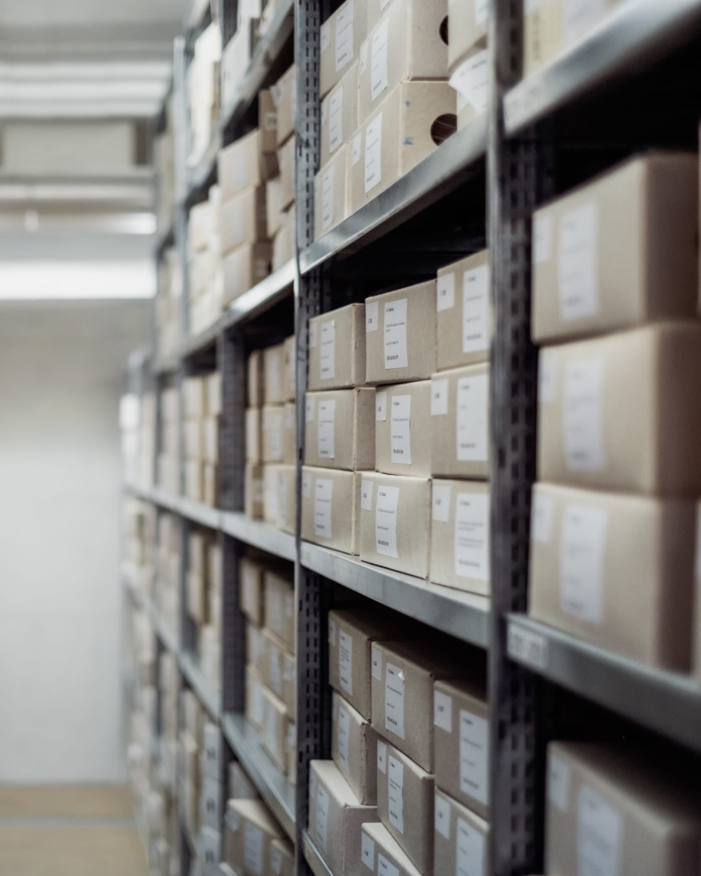 Tall metal shelves of labelled archive boxes in a records store